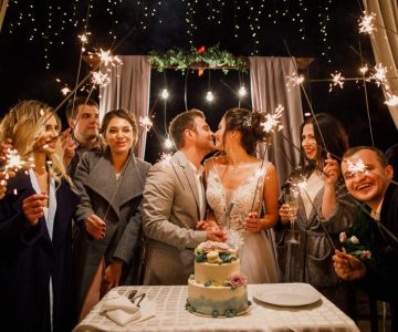young beautiful wedding couple cut wedding cake with friends and